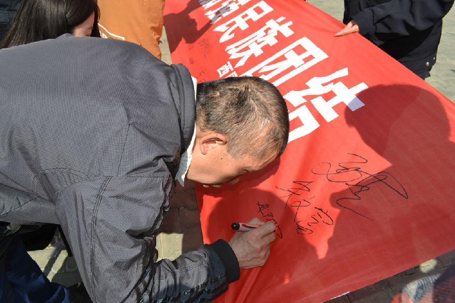 图为肢体残疾人冉阳军参加精神文明、民族团结签名活动