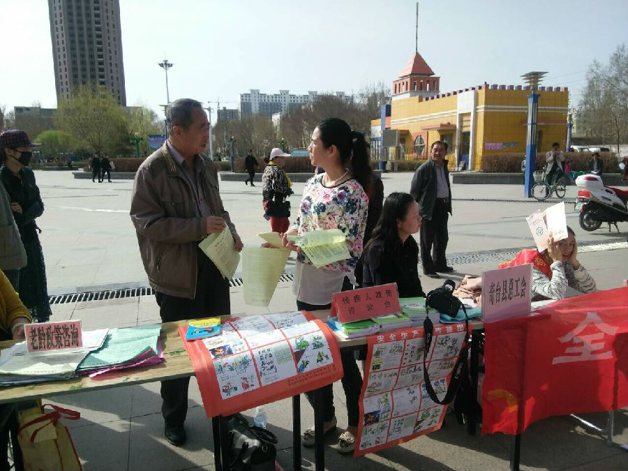 图为残联工作人员向群众讲解残疾人方面的政策