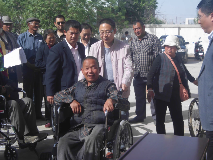 图为尉犁县县人民政府副县长孙志强在为残疾人发放轮椅