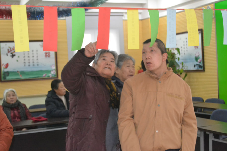 图为肢体残疾人冉阳军和居民一起猜灯谜